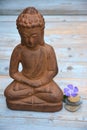 Brown Buddha statue with flowers and zen stones