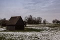 Brown cabin on the icy green field in winter