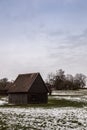 Brown cabin on the icy green field in winter