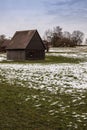 Brown cabin on the icy green field in winter