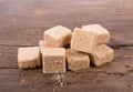 Brown cane sugar cubes on wooden background. top view