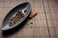 Brown canoe-shaped dish on bamboo mat with coffee beans, star anise, cloves and cinnamon