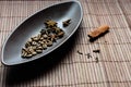 Brown canoe-shaped dish on bamboo mat with coffee beans, star anise, cloves and cinnamon