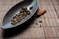 Brown canoe-shaped dish on bamboo mat with coffee beans, star anise, cloves and cinnamon