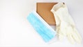 Brown cardboard box,latex white medical gloves and blue medical mask on a white background,copy spaes.Safe delivery of online