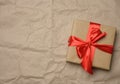 Brown cardboard box tied with a silk red ribbon on a brown paper background Royalty Free Stock Photo