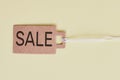 Brown cardboard price tag with sign sale on pastel yellow background