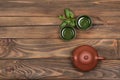 Brown ceramic teapot, two dark green small special cups and fresh mint on a dark wooden planked background. Tea ceremony.