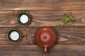 Brown ceramic teapot, two dark green special cups and green tea on a dark wooden planked background. Tea ceremony.