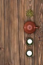 Brown ceramic teapot, two dark green special cups and green tea on a dark wooden planked background. Tea ceremony.