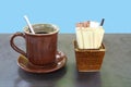 Brown ceramics coffee cup with saucer and paper sachets of sugar and non-dairy creamer in porcelain pot Royalty Free Stock Photo