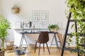 Brown chair at desk in white boho home office interior with plan