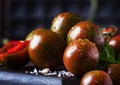 Brown cherry tomatoes with sea salt and green basil on dark table, autumn harvest, selective focus Royalty Free Stock Photo