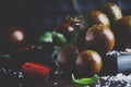 Brown cherry tomatoes with sea salt and green basil on dark table, autumn harvest, selective focus Royalty Free Stock Photo