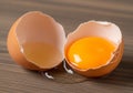 A brown chicken egg is cracked open on a wooden surface. The eggshell is in two halves, with one Royalty Free Stock Photo