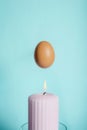 Brown chicken egg with a pink burning candle