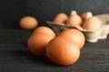 Brown chicken eggs in carton box on wooden table against black background, space for text Royalty Free Stock Photo
