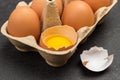 Brown chicken eggs in carton container. Broken egg in container. Shells on table Royalty Free Stock Photo