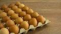 Brown chicken eggs in gray carton package box on wooden table Royalty Free Stock Photo