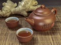 Brown chinese tea set of a teapot and cups and ginger on bamboo table mat . Royalty Free Stock Photo