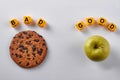 Brown chocolate cookie and green apple on white background. Royalty Free Stock Photo