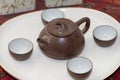 Brown clay Chinese tea set spread out on a white plate