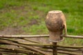 Brown clay pot on a wicker fence in the right side of photo. Royalty Free Stock Photo