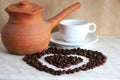 Brown clay Turk for cooking Arabic coffee, white Cup and saucer and roasted coffee beans in the shape of a heart