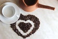 Brown clay Turk for cooking Arabic Turkish coffee, white clean Cup and saucer and roasted coffee beans in the shape of a