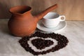 Brown clay Turk for cooking Turkish coffee, white Cup and saucer and roasted coffee beans in the shape of a heart