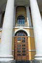 Brown closed wooden door on a yellow wall with a balcony Royalty Free Stock Photo