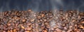 Brown coffee beans are roasting on a dark background. Steam, smoke. Close-up. Banner Royalty Free Stock Photo