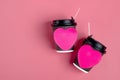 Brown coffee cups, red heart-shaped sticker on pink background.