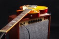 Brown combo amplifier for electric guitar with honey sunburst guitar on black background