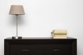 Brown commode with lamp and books in minimalism interior Royalty Free Stock Photo