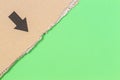 Brown corrugated cardboard ragged edge with black arrow on green background Royalty Free Stock Photo