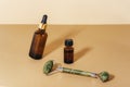 Brown cosmetic serum bottle, essential oil and jade facial roller on neutral beige background. Natural skin care Royalty Free Stock Photo