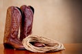 Brown cowboy boots and a coil of rope on brown