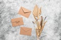 Brown craft envelopes and a bouquet of dried flowers and grass on a gray grunge background. Greeting card. Top view Royalty Free Stock Photo
