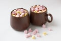 Brown cups of hot cocoa with marshmallows in heart shape on white background Royalty Free Stock Photo