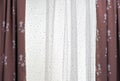 Brown curtains with floral patterns and white tulle on the living room window