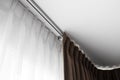 Brown curtains and white tulle on a rail with a white ceiling. Curtain interior decoration in living or sleeping room