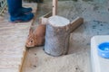 A brown cute rabbit trying to hide behind the log in the zoo with boots of zoo keeper in the back, little bunny Royalty Free Stock Photo