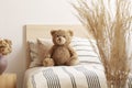 Brown cute teddy bear on single wooden bed with striped bedding Royalty Free Stock Photo