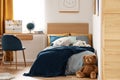 Brown cute teddy bear on wooden floor of stylish bedroom interior for kids