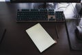 A brown desk with a black keyboard with blue lights, a mouse apencil and a tablet