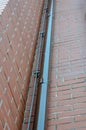 Brown drainpipe against a brick wall. Gutter and grounding line Royalty Free Stock Photo