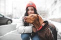 Brown dressed dog of the magyar breed looks at the side, but the smiling girl in warm clothes on the blurred background. Focus on Royalty Free Stock Photo