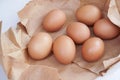 Brown egg in paper bag behind on a light colored background,Fresh chicken eggs on wood table