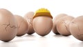 Brown egg with yellow hardhat standing out among cracked eggs. 3D illustration Royalty Free Stock Photo